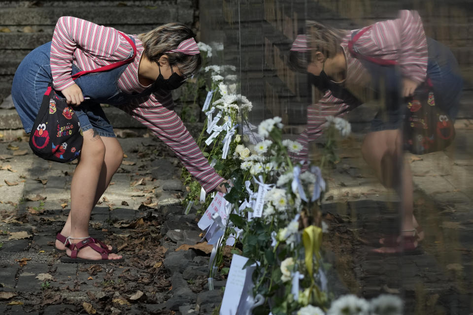 FILE - An activist lays flowers in front of a wall with names of martyrs and heroes who were the victims of the abuses of the Ferdinand Marcos Sr. dictatorship at the "Bantayog ng mga Bayani" or Monument to the Heroes in Quezon city, Philippines as they condemn the 5th anniversary of the burial of the late dictator on Nov. 18, 2021. Filipino voters overwhelmingly elected Ferdinand "Bongbong" Marcos Jr., the son of the nation’s notorious former dictator, as president during the May 2022 elections, completing a stunning return to power for the Marcos clan, which ruled the country for more than two decades until being ousted in 1986 in the nonviolent “People Power” revolution. (AP Photo/Aaron Favila, File)