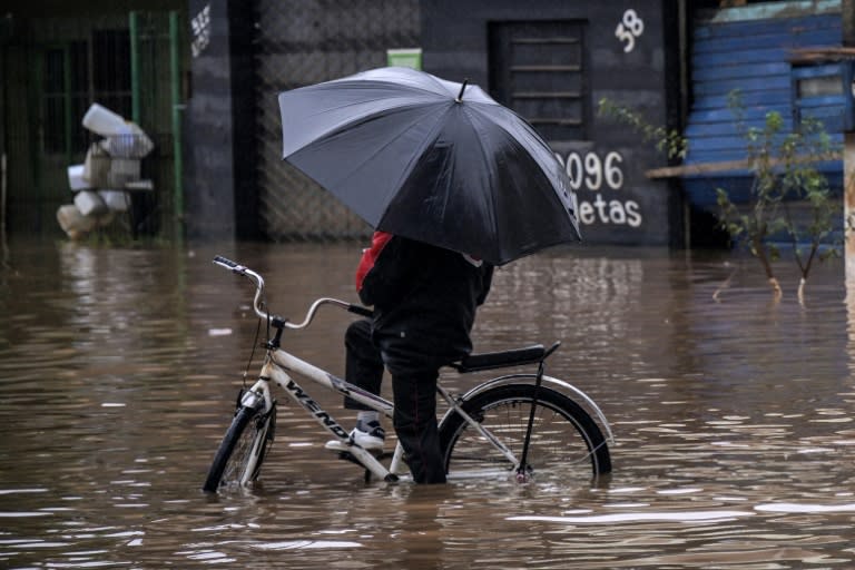 A local attempts to ride a bike in a flooded street at Santos Dumont neighbourhood in Sao Leopoldo, Rio Grande do Sul, Brazil, on May 12, 2024 (Nelson ALMEIDA)