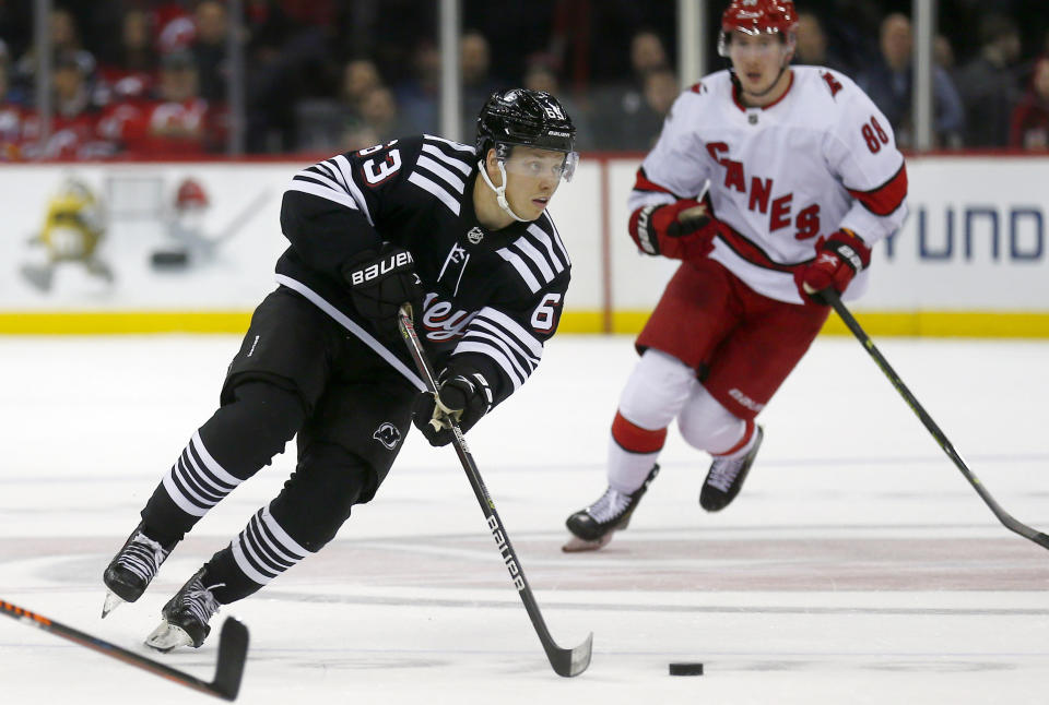 New Jersey Devils forward Jesper Bratt (63) skates with the puck while Carolina Hurricanes center Martin Necas trails during the first period of an NHL hockey game Sunday, Jan. 1, 2023, in Newark, N.J. (AP Photo/John Munson)