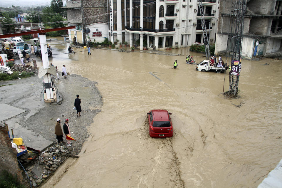People and vehicles navigate through flooded roads after heavy monsoon rains in Mingora, the capital of Swat valley in Pakistan, Saturday, Aug. 27, 2022. Officials say flash floods triggered by heavy monsoon rains across much of Pakistan have killed nearly 1,000 people and displaced thousands more since mid-June. (AP Photo/Naveed Ali)