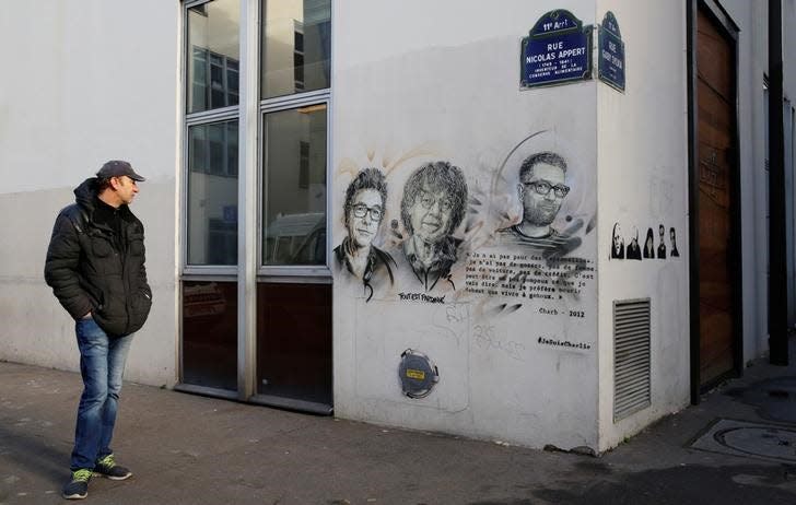 A man pauses outside the old offices of the satirical Charlie Hebdo magazine where two brothers armed with assault rifles shot and killed 11 people, including most of the publication's cartoonists and writers, on January 7, 2015, as France pays tribute two years later in Paris, France, January 5, 2017.  REUTERS/Jacky Naegelen 