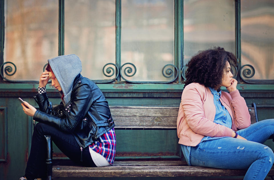 Girlfriends in conflict are sitting on the bench and sulking each other