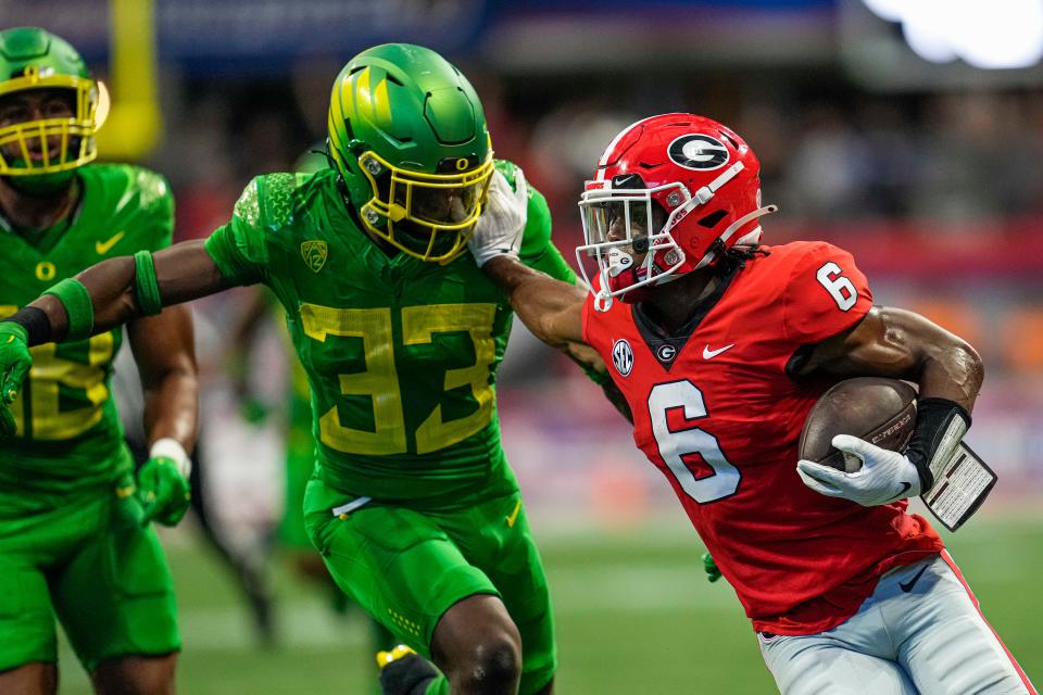 Georgia Bulldogs running back Kenny McIntosh (6) runs against Oregon Ducks linebacker Jeffrey Bassa (33) during the first half at Mercedes-Benz Stadium in Atlanta, Georgia, in September 2022.