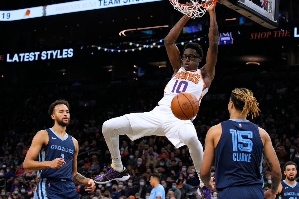 Phoenix Suns forward Jalen Smith (10) dunks over Memphis Grizzlies forwards Kyle Anderson (1) and Brandon Clarke during the first half of an NBA basketball game Monday, Dec. 27, 2021, in Phoenix.