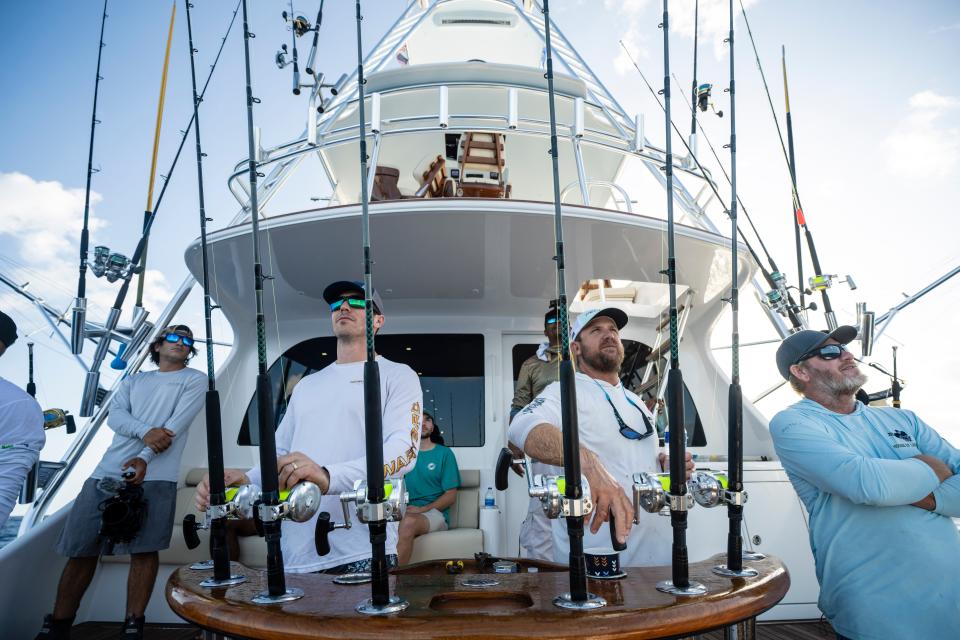 The Dolphins players and guides stand by their fishing poles during the FINS Weekend Fishing Tournament in Coconut Grove.