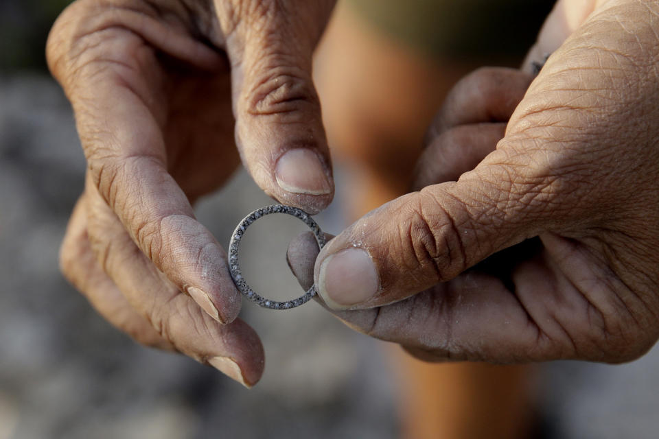 Bernadette Laos looks at jewelry she salvaged from her home that was destroyed by the Kincade Fire near Geyserville, Calif., Thursday, Oct. 31, 2019. (AP Photo/Charlie Riedel)