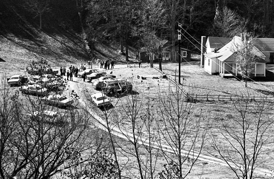 Police officials and media mill around the farm Nov. 11, 1973 where David (Stringbean) Akeman, 57, and his wife, Estelle, 59, was found murdered. The couple lived in the three-room, red cottage, left of the larger, white frame house.