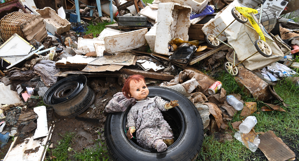 Damaged household items litter the street after flooding.