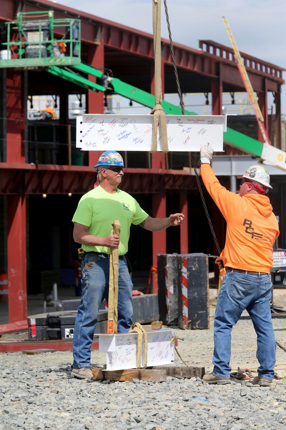 Steelworkers Mark Davis (left), Bear, and Rob Minor, Milford, position the signed steel beams that will top off the construction at the EastSide Charter School in Wilmington, DE, Monday, April 8, 2024.