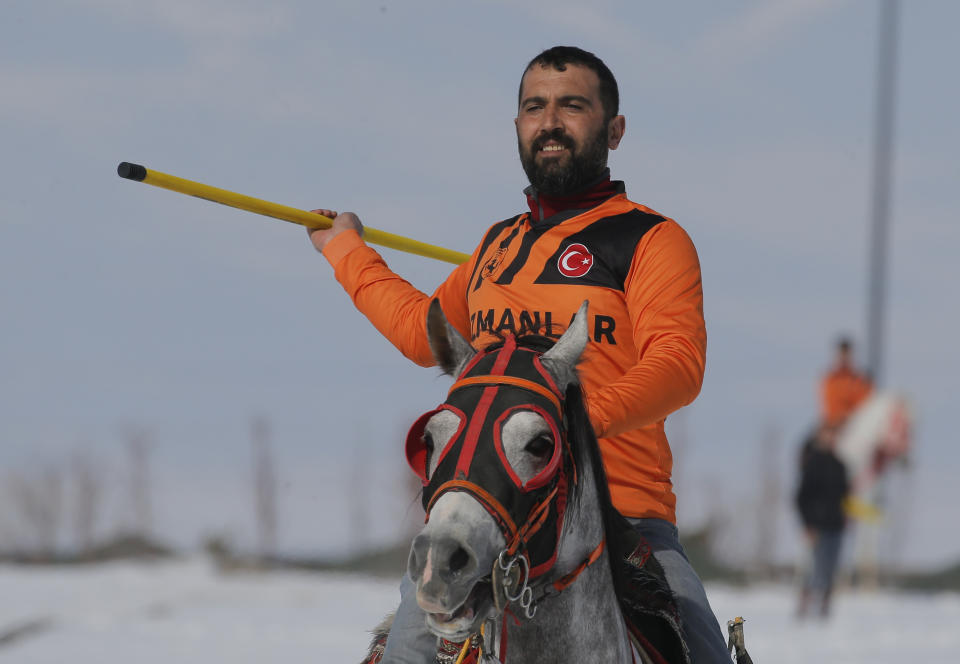 A rider is about to throw the the javelin during a game of Cirit, a traditional Turkish equestrian sport that dates back to the martial horsemen who spearheaded the historical conquests of central Asia's Turkic tribes, between the Comrades and the Experts local sporting clubs, in Erzurum, eastern Turkey, Friday, March 5, 2021. The game that was developed more than a 1,000 years ago, revolves around a rider trying to spear his or her opponent with a "javelin" - these days, a rubber-tipped, 100 centimeter (40 inch) length of wood. A rider from each opposing team, which can number up to a dozen players, face each other, alternately acting as the thrower and the rider being chased. Cirit was popular within the Ottoman empire, before it was banned as in the early 19th century. However, its popularity returned as is now one of many traditional sports encouraged by the government and tournaments are often arranged during festivals or to celebrate weddings. (AP Photo/Kenan Asyali)