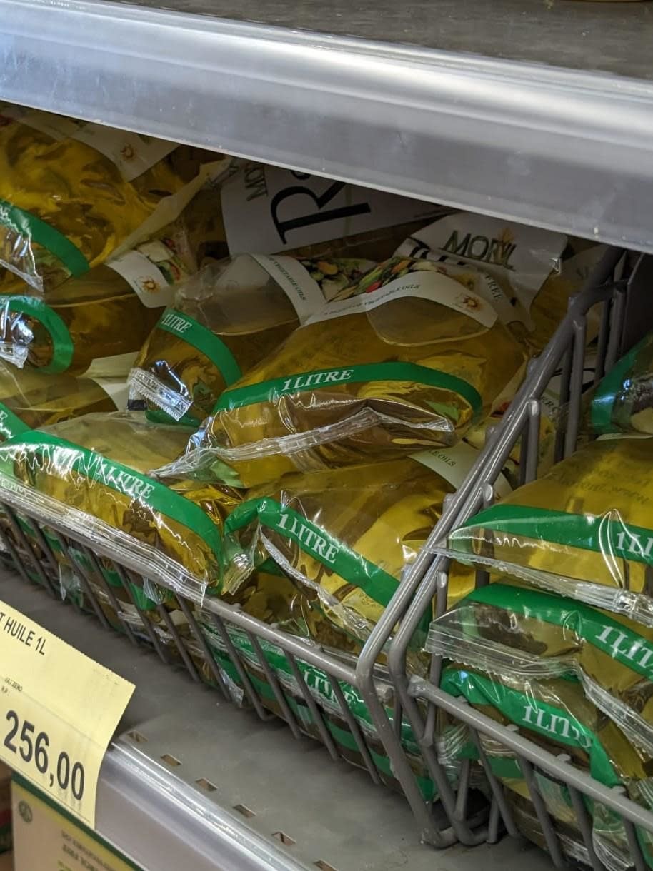 Bags of 1-liter cooking oil sitting on a grocery store shelf, priced at 256.00 of the local currency