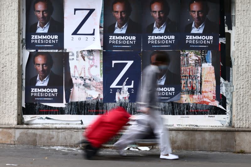 A woman walks past posters in support of French far-right commentator Eric Zemmour in Paris