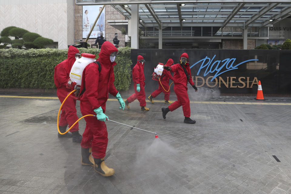 Indonesian firefighters spray disinfectant to help curb the spread of the new coronavirus outbreak on a sidewalk at the main business district in jakarta, Indonesia, Saturday, June 20, 2020. (AP Photo/Achmad Ibrahim)