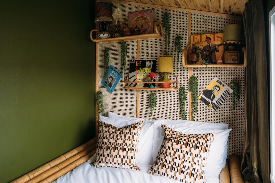 AFTER: Anna replaced the single beds for a double and created a bed frame out of bamboo for a tiki feel. The wall opposite the bed (not pictured) was covered with a bronze-acrylic mirror to create the illusion of extra space. Most of the furnishings, including the rattan shelves and lampstands, are vintage. Part of the “Jungle Room”’s mood board was Elvis Presley’s Jungle Room in Graceland. “So tacky and ridiculous,” says Anna. “But so fun.”