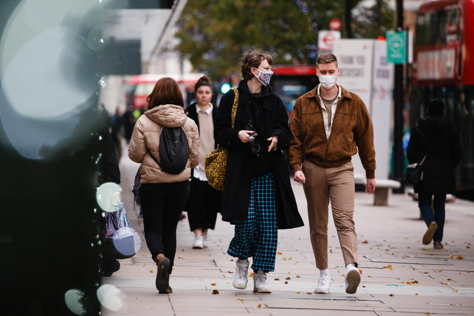 People wearing face masks walk along Oxford Street in London, England, on November 6, 2020. England yesterday began its second national coronavirus lockdown, announced by British Prime Minister Boris Johnson last Saturday, citing fears that covid-19 again threatened to overwhelm the National Health Service (NHS). Pubs, bars, restaurants and non-essential shops are all required to be closed until the currently scheduled end date of December 2. People have meanwhile been asked to stay home as much as possible, although schools and other educational institutions are this time being being kept open and the streets of central London today were markedly busier than the early days of the first lockdown in the spring. (Photo by David Cliff/NurPhoto via Getty Images)