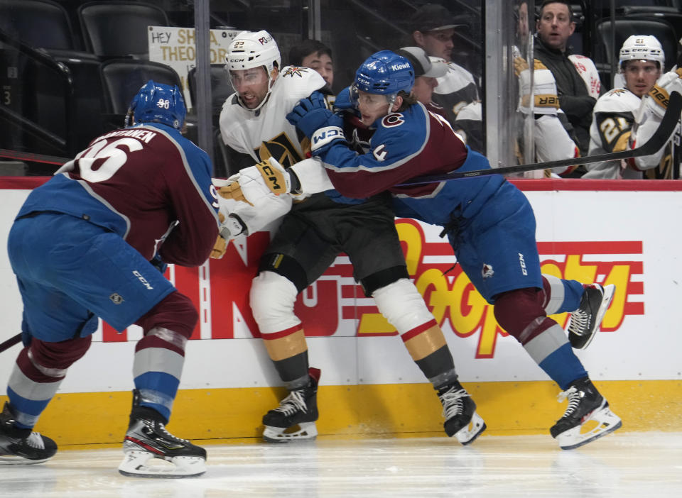 Vegas Golden Knights right wing Michael Amadio, center, is checked by Colorado Avalanche defenseman Bowen Byram, right, as Avalanche right wing Mikko Rantanen comes in to collect the puck in the second period of an NHL hockey game Monday, Feb. 27, 2023, in Denver. (AP Photo/David Zalubowski)