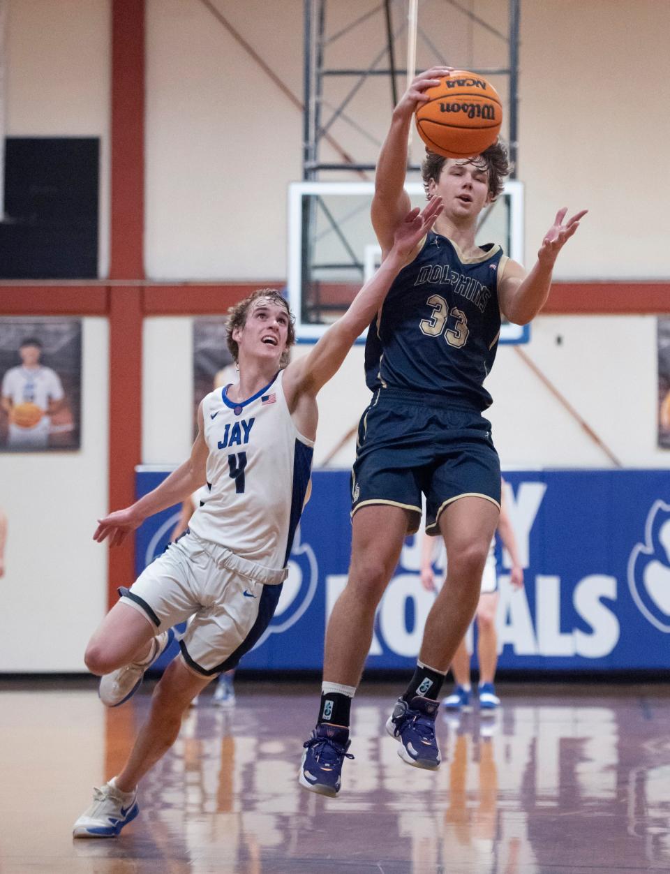 Ethan McDonald (4) fouls Reece Bloomberg (33) as he leaps for a high inbounds pass during the Gulf Breeze vs Jay boys basketball game at Jay High School on Tuesday, Jan. 18, 2022.