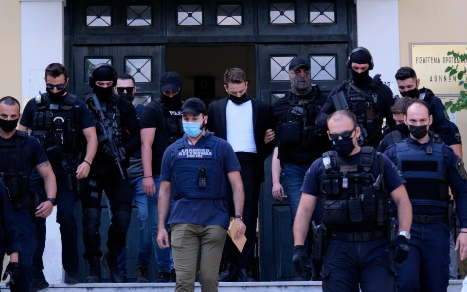 Babis Anagnostopoulos, center, escorted by police leaves the court in Athens, Friday - AP