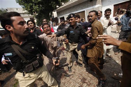 Angry Christian men push a policeman out of a church after a blast in Peshawar September 22, 2013. REUTERS/Fayaz Aziz