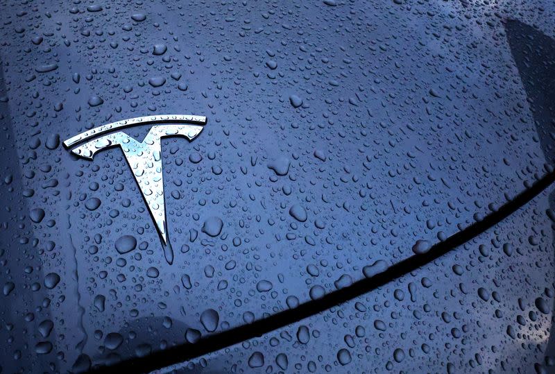 The logo of a Tesla electric vehicle is placed on a car outside a dealership in Drogenbos