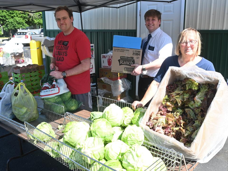 Volunteers Deborah Marsh, Brett Parkinson, and Seth Buxton hand out lettuce grown at the Lakeland Corrections horticultural unit. Buxton and Parkinson are volunteer missionaries from the Church of Jesus Christ of Latter-Day Saints serving the area.