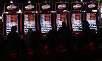 FILE - In this July 23, 2019 file photo, slot machine players are silhouetted on the floor of the casino at the WinStar World Casino and Resort in Thackerville, Okla. For the last 15 years, casino gambling has been a financial boon for Oklahoma and many of the Native American tribes located there. (AP Photo/Sue Ogrocki)