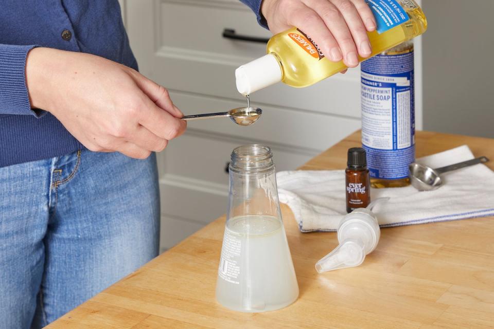 Woman making foaming hand soap adds carrier oil to recipe.