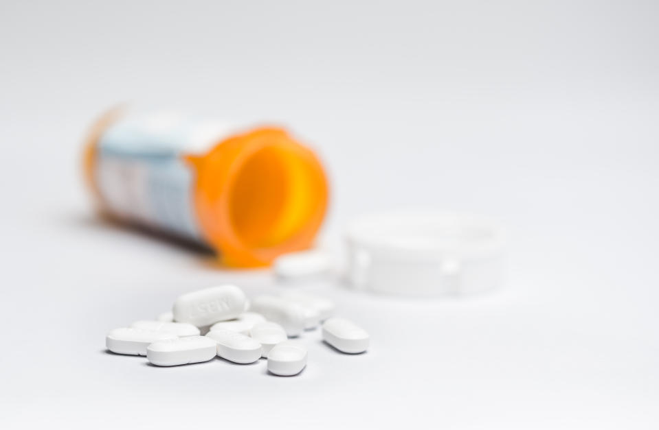 Close-Up Of Medicines Spilling From Bottle Against Gray Background