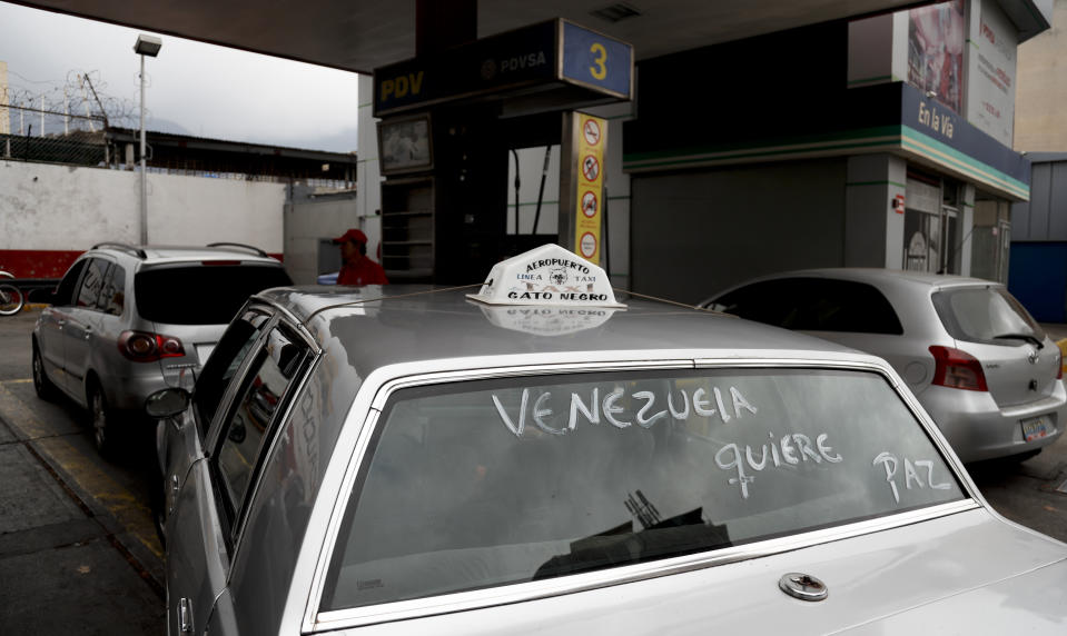 A taxi cab with a message on the windshield the reads in Spanish "Venezuela wants peace" waits its turn to fill up its gas tank, at one of the few fuel stations that has electricity, during rolling blackouts in Caracas, Venezuela, Monday, March 11, 2019. An explosion rocked a power station Monday in the Venezuelan capital, witnesses said, adding to the crisis created by days of nationwide power cuts, while opposition leader Juan Guaido has blamed the blackouts that began Thursday on alleged government corruption and mismanagement. (AP Photo/Eduardo Verdugo)