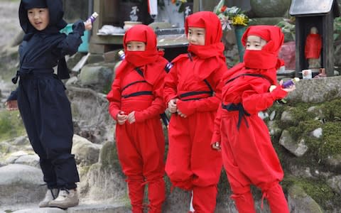 Children dressed as ninjas pose for a souvenir picture during a ninja festival in Iga - Credit: Reuters