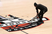 Workers remove decals from the court after the cancelation of the 2020 Atlantic 10 men's basketball tournament prior to the second round at Barclays Center on March 12, 2020 in the Brooklyn borough of New York City. The tournament was canceled amid growing concerns of the spread of COVID-19 (Coronavirus.) (Photo by Mike Lawrie/Getty Images)