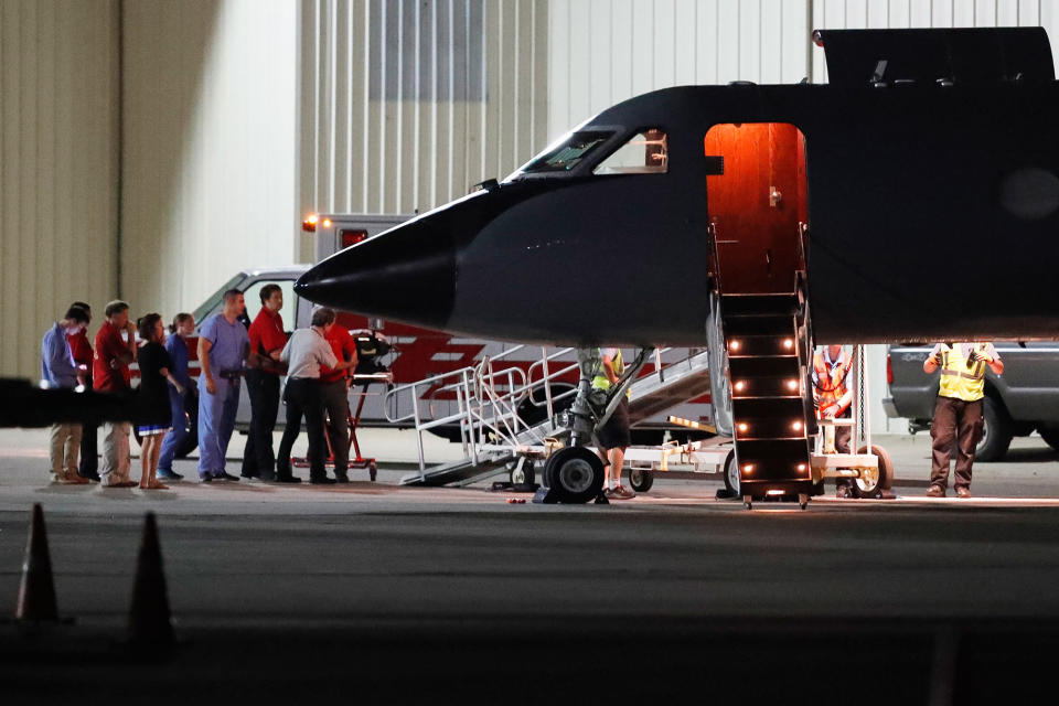 Medical personnel and visitors gather at the transport plane