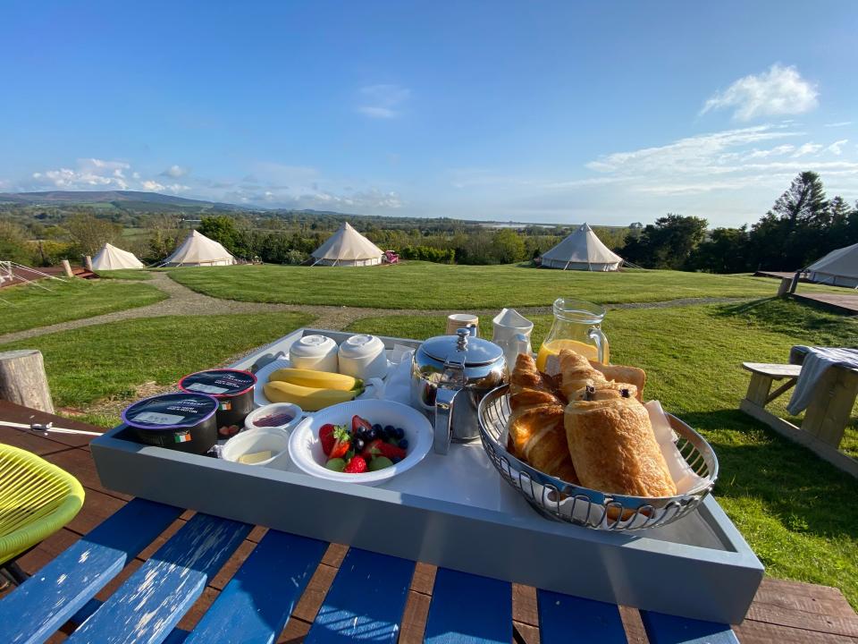 Tray of breakfast overlooking tents on a camping trip