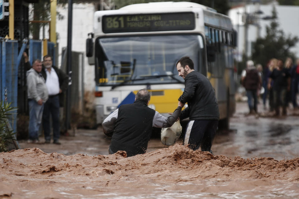 <p>AA man helps another one to walk in a flooded street following a heavy rainfall in the town of Mandra, Greece, Nov. 15, 2017. (Photo: Xinhua/Marios Lolos via Getty Images) </p>