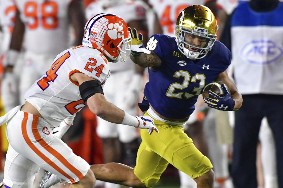 Notre Dame running back Kyren Williams (23) fends off Clemson Tigers safety Nolan Turner (24) on his way to a touchdown during the first quarter of an NCAA college football game Saturday, Nov. 7, 2020, in South Bend, Ind. (Matt Cashore/Pool Photo via AP)