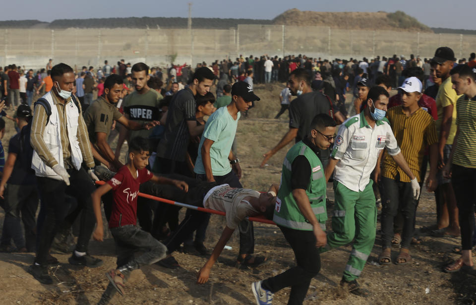 Medics evacuate a wounded person from the fence of Gaza Strip border with Israel, during a protest marking the anniversary of a 1969 arson attack at Jerusalem's Al-Aqsa mosque by an Australian tourist later found to be mentally ill, east of Gaza City, Saturday, Aug. 21, 2021. (AP Photo/Adel Hana)