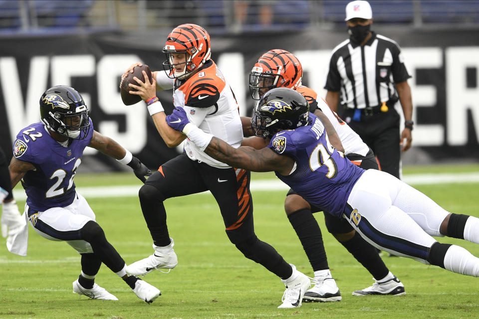 Cincinnati Bengals quarterback Joe Burrow, center, scrambles for yardage against Baltimore Ravens cornerback Jimmy Smith (22) and outside linebacker Matt Judon (99) during the first half of an NFL football game, Sunday, Oct. 11, 2020, in Baltimore. (AP Photo/Nick Wass)