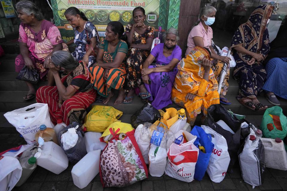FILE- Women wait near an empty fuel station hoping to buy kerosene oil for cooking in Colombo, Sri Lanka, Thursday, May 26, 2022. Sri Lankan President Ranil Wickremesinghe said Saturday, July 30, that an agreement with the International Monetary Fund to help pull the bankrupt nation out of its economic crisis is pushed back to September because of unrest over the past weeks. (AP Photo/Eranga Jayawardena, File)