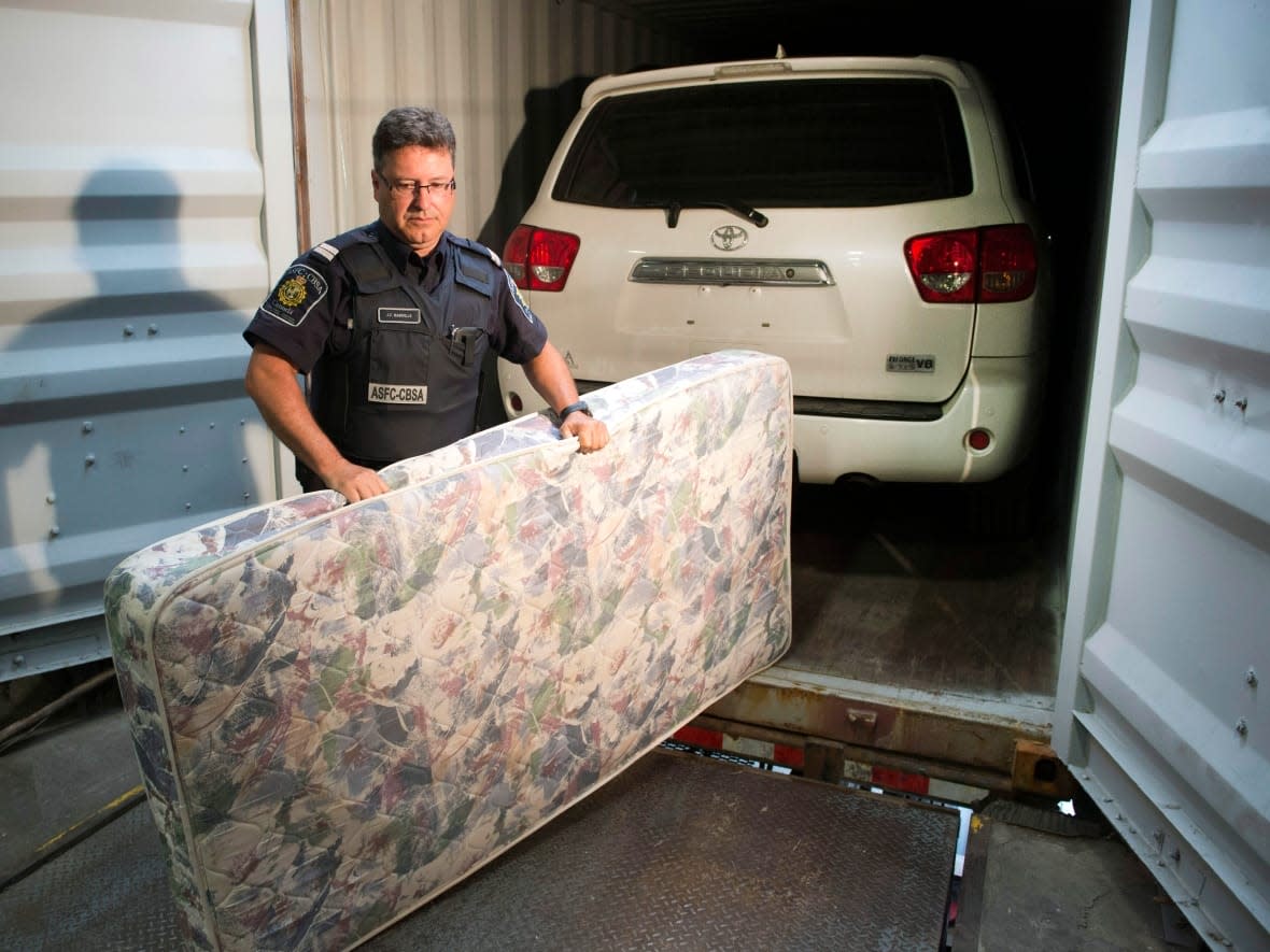 CBSA Superintendent Jean-Francois Rainville removes a mattress that was used to hide a stolen Toyota Sequoia in a container at a news conference on Thursday, July 17, 2014 in Montreal. (Ryan Remiorz/The Canadian Press - image credit)