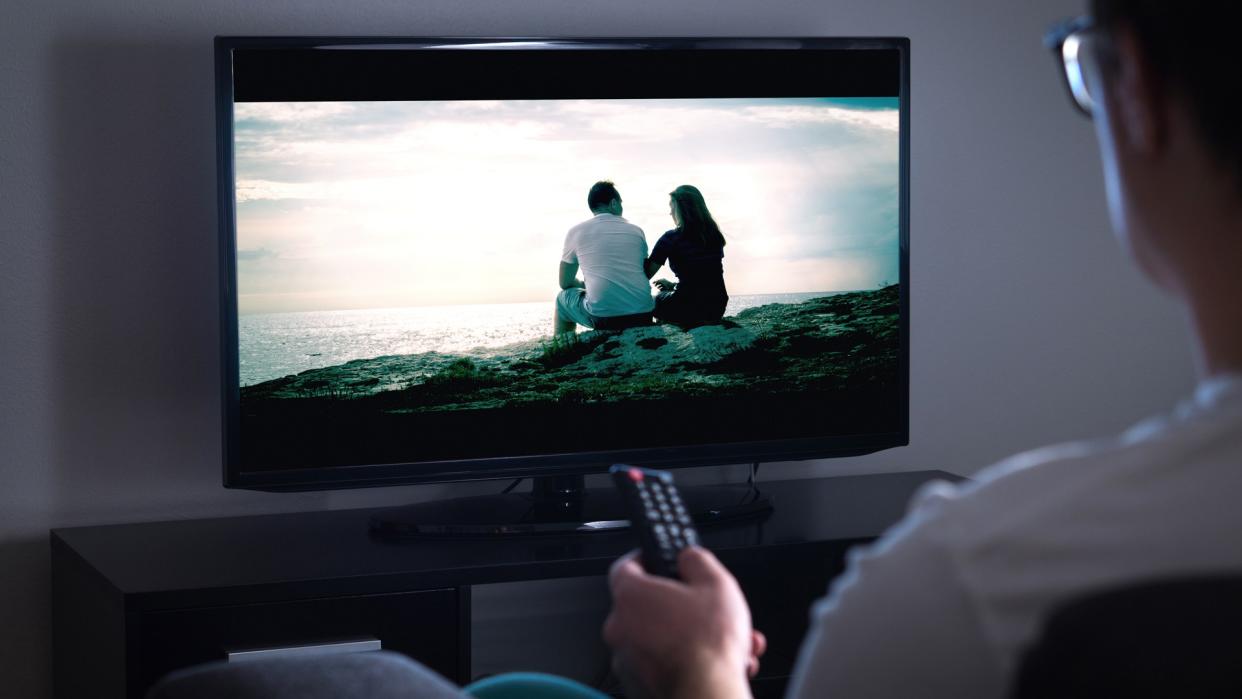 Man watching tv or streaming movie or series with smart tv at home.