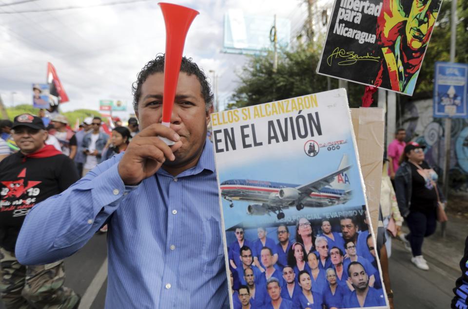 A demonstrator holds a poster with a message that reads in Spanish; "They all fit in the plane", referring to prisoners of the government of President Daniel Ortega who were released, stripped of their citizenship and flown to the United States, during a pro-government march in Managua, Nicaragua, Saturday, Feb. 11, 2023. (AP Photo)