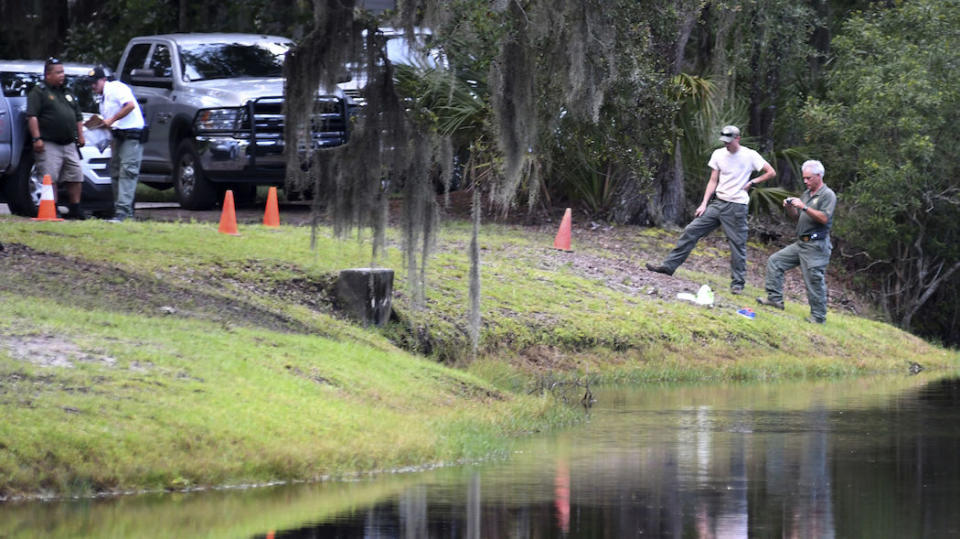 Police take pictures of the site where a woman was killed by an alligator (Picture: AP)