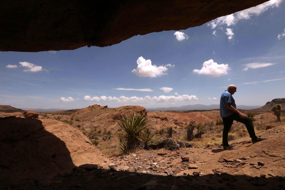 A man stands outside a rock ledge.