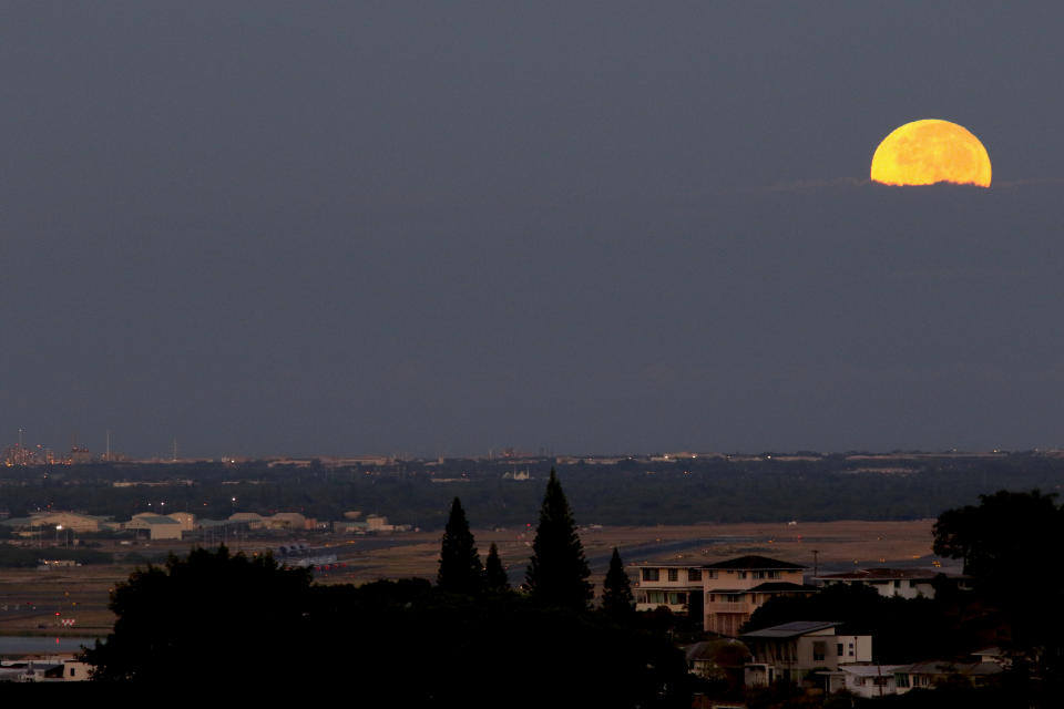 The moon sets behind a runway at the international airport in Honolulu, Thursday, Oct. 1, 2020. After a summer marked by a surge of coronavirus cases in Hawaii, officials plan to reboot the tourism based economy later this month despite concerns about the state's pre-travel testing program. (AP Photo/Caleb Jones)