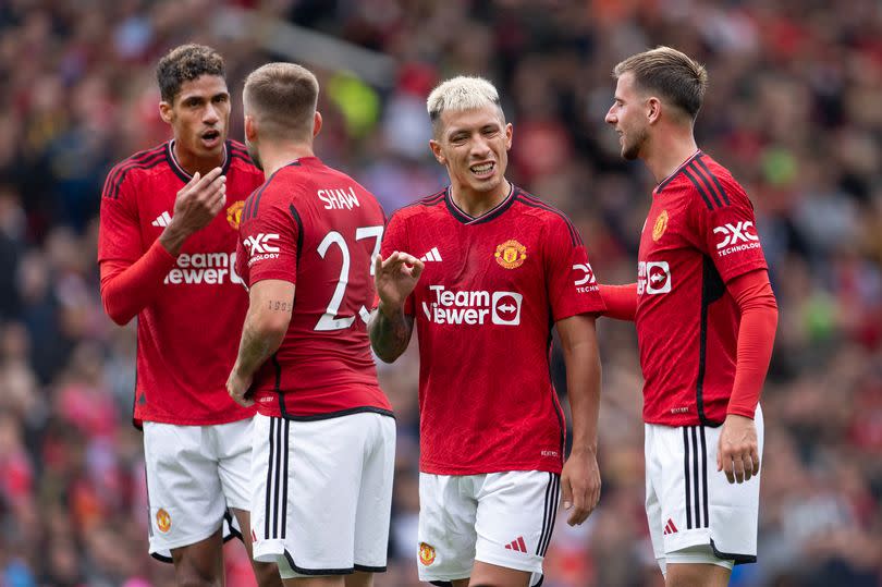 Raphael Varane, Luke Shaw, Lisandro Martinez and Mason Mount stand in conversation mid-game for Manchester United.