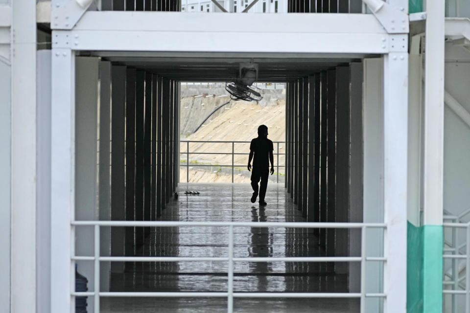 A worker is silhouetted as he walks on the hallway of a building at the construction site of the new capital city in Penajam Paser Utara, East Kalimantan, Indonesia, Wednesday, March 8, 2023. Officials promise a "sustainable forest city" that puts the environment at the heart of the development and aims to be carbon-neutral by 2045. But the project has been plagued by criticism from environmentalists and Indigenous communities, who say it degrades the environment, further shrinks the habitat of endangered animals such as orangutans and displaces Indigenous communities that rely on the land for their livelihoods. (AP Photo/Achmad Ibrahim)