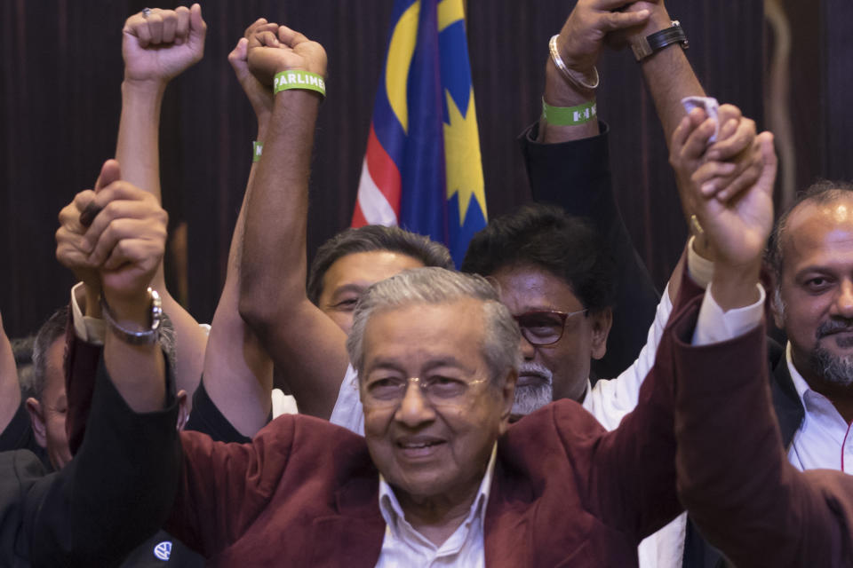 FILE - Mahathir Mohamad, center, celebrates during a meeting of coalition leaders at a hotel in Kuala Lumpur, Malaysia on May 9, 2018. At 97, Mahathir is back again in the election race as the head of a new ethnic Malay alliance that he calls a "movement of the people." He hopes his bloc could gain enough seats in Nov. 19 polls to be a powerbroker. (AP Photo/Vincent Thian, File)