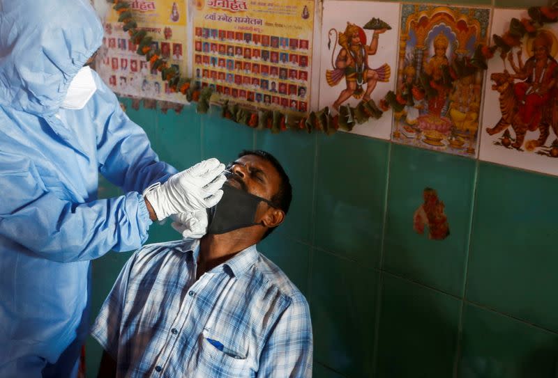 FILE PHOTO: A health worker in personal protective equipment (PPE) collects a swab sample from a man in Mumbai