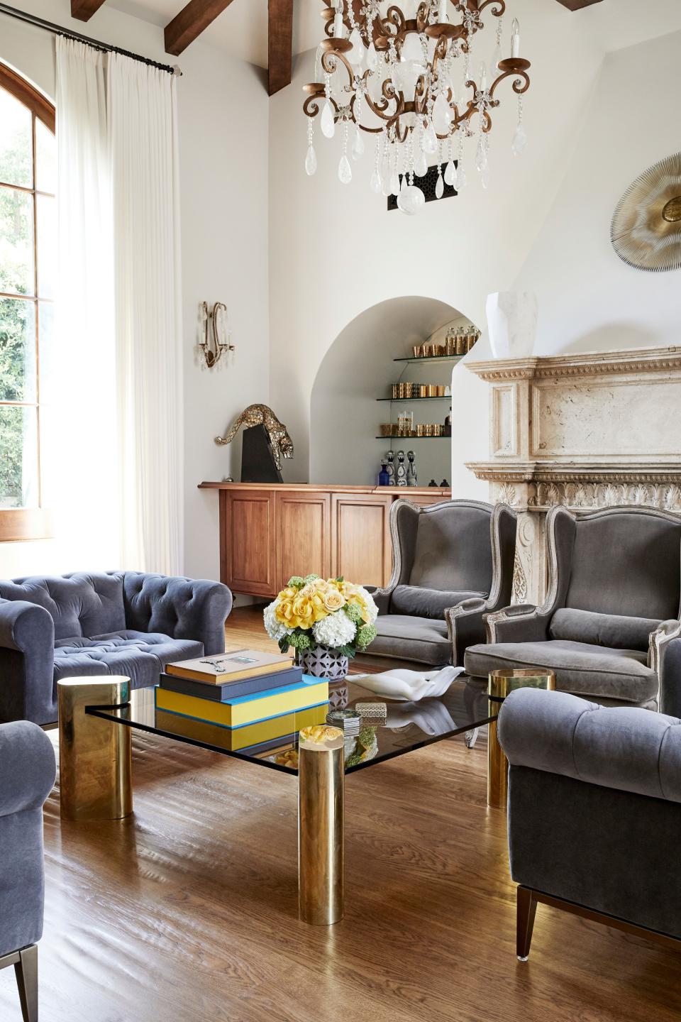 A second view of the living room displays the bar, which was also custom-designed by Farahan. The fireplace is hand-carved and made of travertine; in front of it are two wingback chairs from RH.