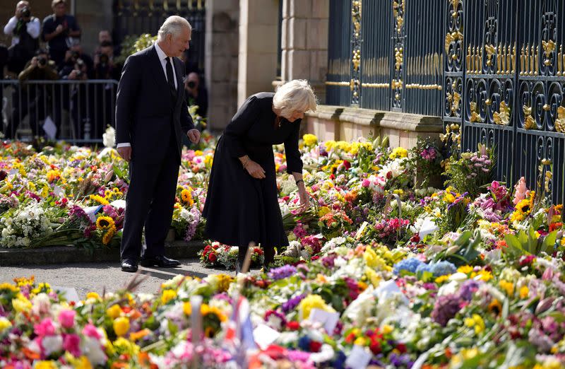 El rey Carlos III y la reina consorte ven las ofrendas florales dejados fuera del castillo de Hillsborough, condado de Down, Irlanda del Norte, tras la muerte de la reina Isabel II el jueves